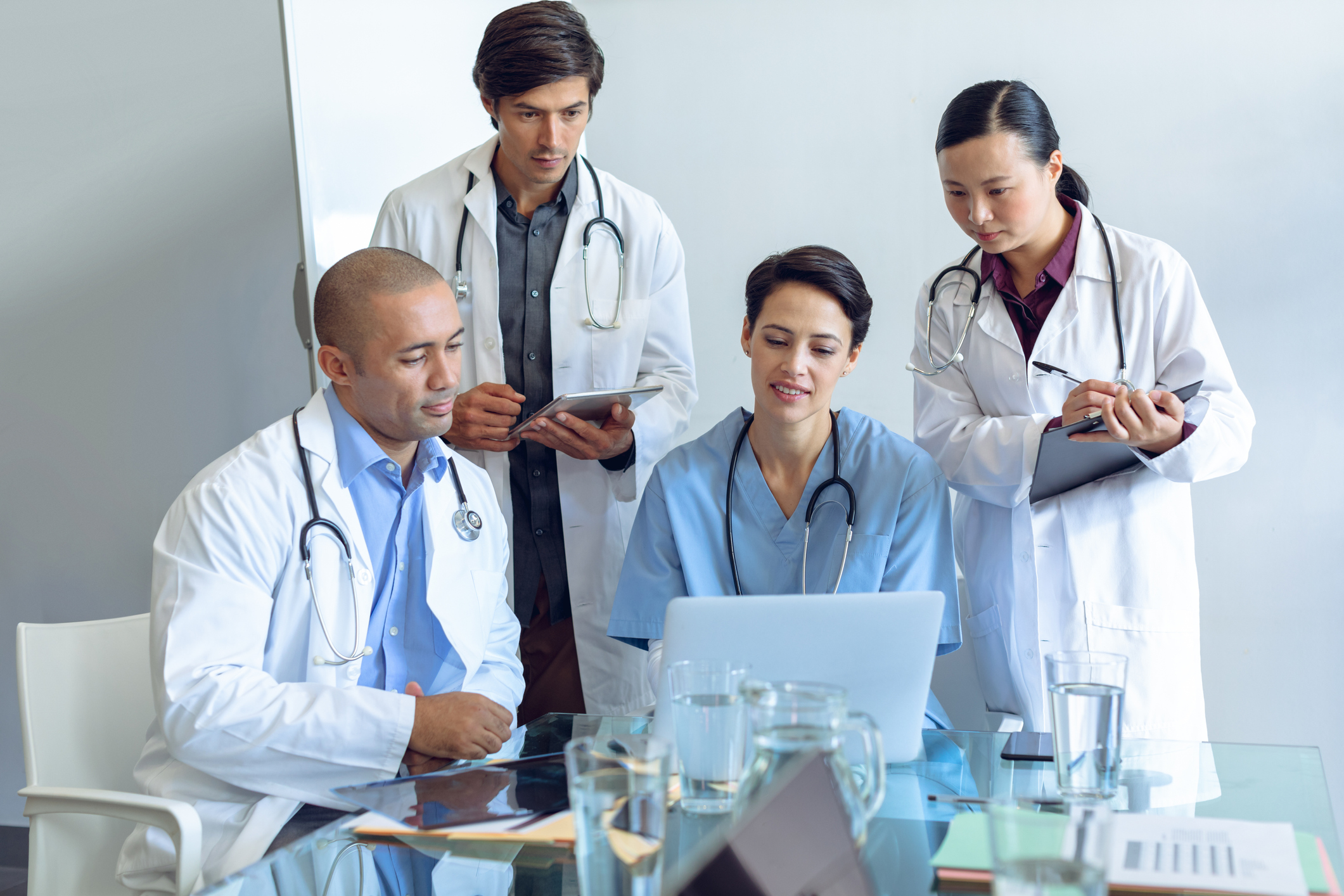 Medical team discussing over laptop at the table in hospital Front view of diverse medical team discussing over laptop at the table of conference room in hospital